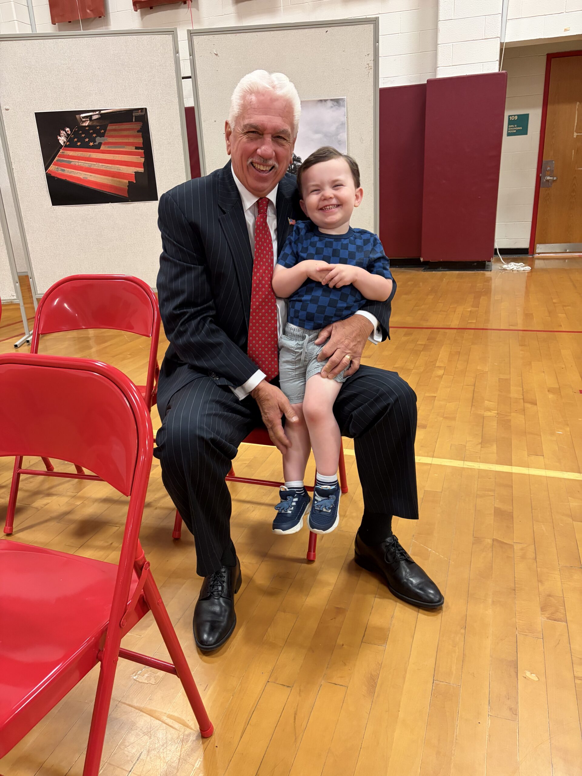 Tom Walsh seated in a gym with a young child